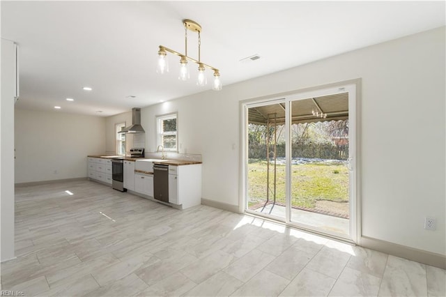 kitchen with visible vents, dishwasher, wall chimney range hood, hanging light fixtures, and stainless steel range with electric stovetop