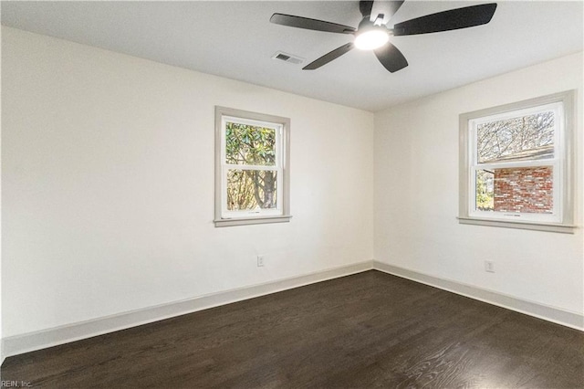 unfurnished room with ceiling fan, dark wood finished floors, visible vents, and baseboards