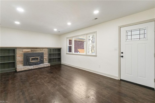 unfurnished living room with a stone fireplace, recessed lighting, dark wood-type flooring, visible vents, and baseboards