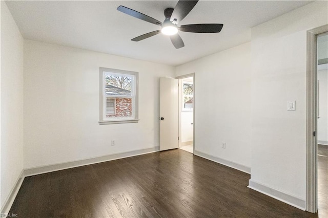 empty room with a ceiling fan, dark wood finished floors, and baseboards