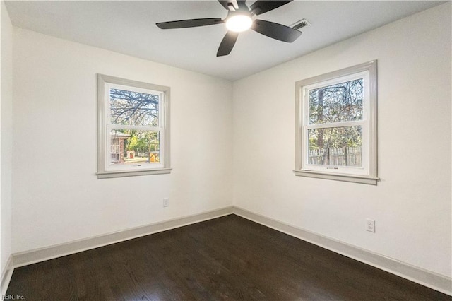 spare room with visible vents, plenty of natural light, baseboards, and wood finished floors