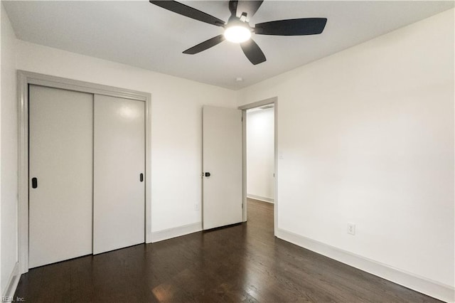 unfurnished bedroom featuring dark wood-style floors, ceiling fan, a closet, and baseboards