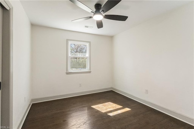 unfurnished room with dark wood-style floors, visible vents, and baseboards