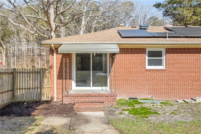 view of side of home with entry steps, brick siding, and fence