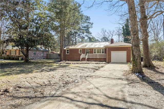 ranch-style house with a garage, covered porch, brick siding, concrete driveway, and a chimney