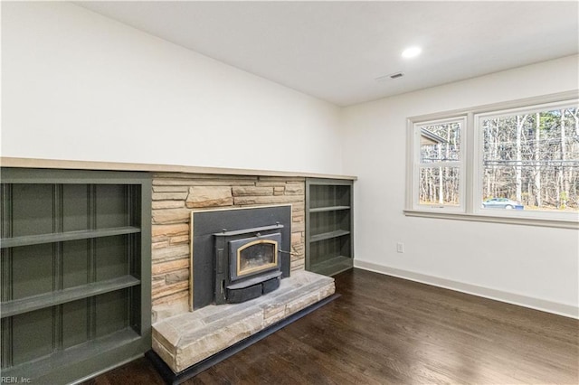 living area featuring visible vents, baseboards, dark wood-style flooring, a wood stove, and recessed lighting