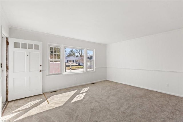 carpeted entryway with baseboards, visible vents, and crown molding