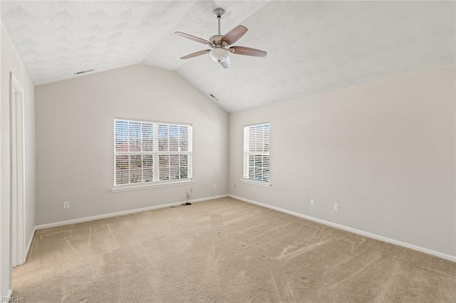 spare room featuring light carpet, vaulted ceiling, a ceiling fan, and baseboards