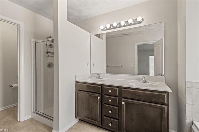 full bath featuring tile patterned floors, a sink, a shower stall, and double vanity