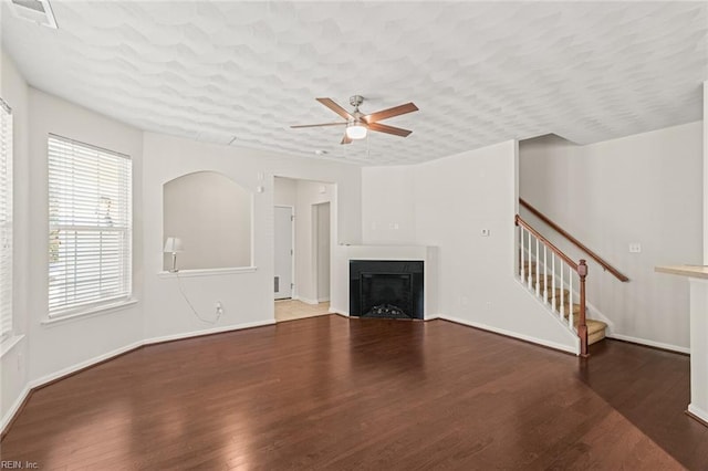 unfurnished living room featuring visible vents, a ceiling fan, wood finished floors, stairs, and a fireplace