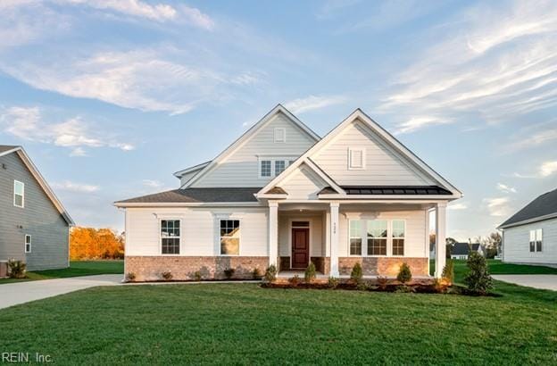 view of front of house with metal roof, a porch, brick siding, a standing seam roof, and a front yard