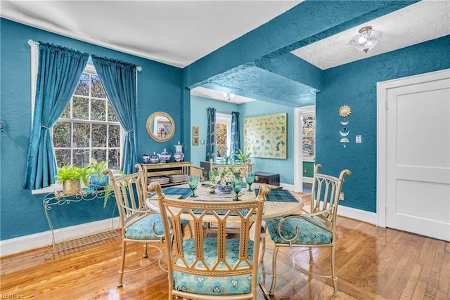 dining room featuring baseboards, wood finished floors, and a textured wall