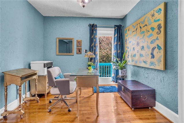 sitting room featuring a textured wall, wood finished floors, and baseboards