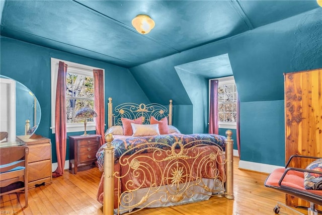 bedroom featuring hardwood / wood-style flooring, baseboards, and vaulted ceiling