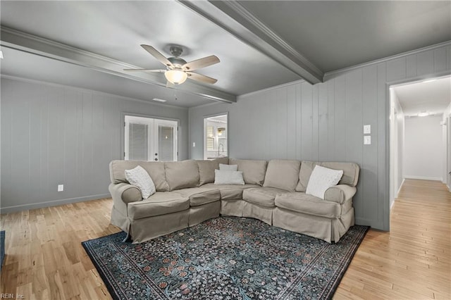 living area with light wood-style floors, french doors, crown molding, and beamed ceiling