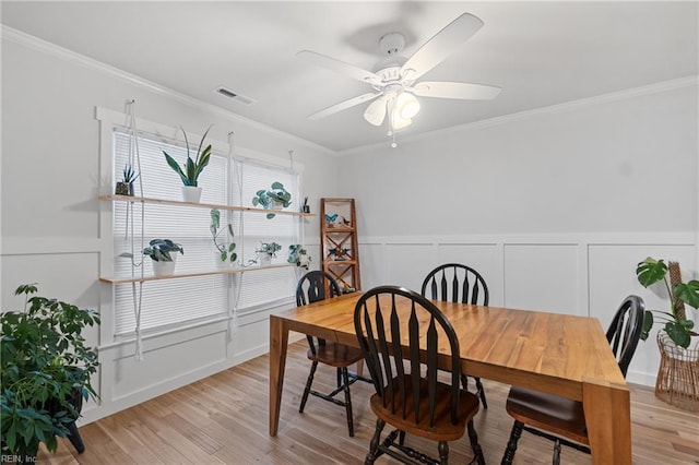 dining room featuring light wood-type flooring, ceiling fan, visible vents, and crown molding