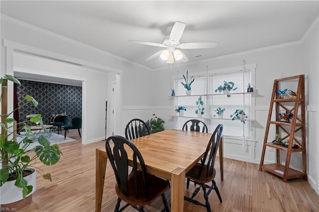 dining room featuring light wood-style floors, ceiling fan, baseboards, and crown molding