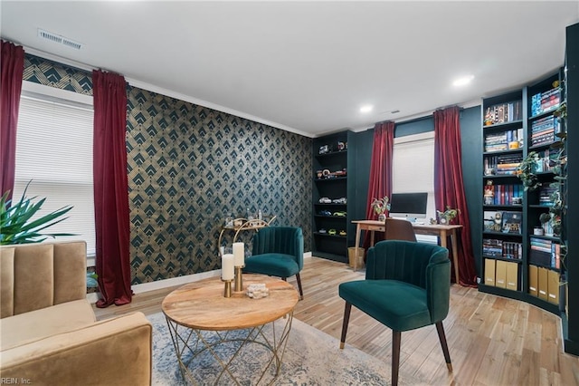 living area featuring light wood-type flooring, visible vents, baseboards, and wallpapered walls