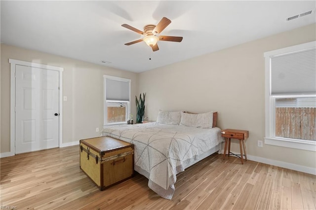 bedroom with light wood-style floors, baseboards, visible vents, and ceiling fan