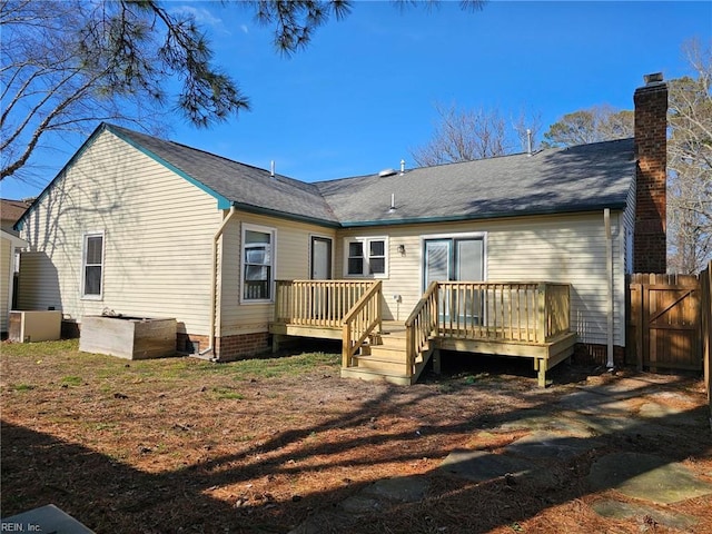 rear view of property featuring a chimney, fence, and a wooden deck