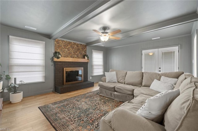 living room with crown molding, a fireplace, beam ceiling, and wood finished floors