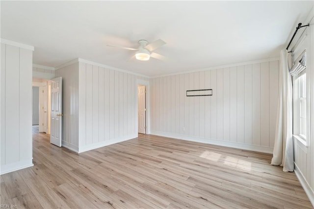 spare room featuring light wood finished floors, ceiling fan, ornamental molding, and baseboards