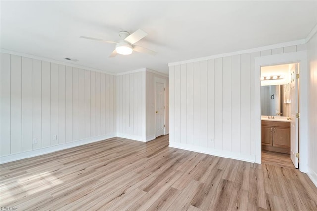 spare room featuring ornamental molding, light wood-type flooring, visible vents, and baseboards