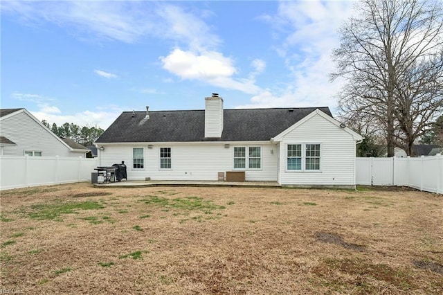 rear view of property featuring a lawn, a chimney, and a fenced backyard