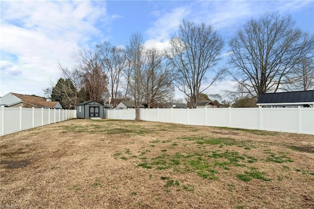 view of yard featuring a shed, a fenced backyard, and an outbuilding