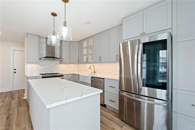 kitchen with backsplash, appliances with stainless steel finishes, light wood-style floors, a sink, and a kitchen island