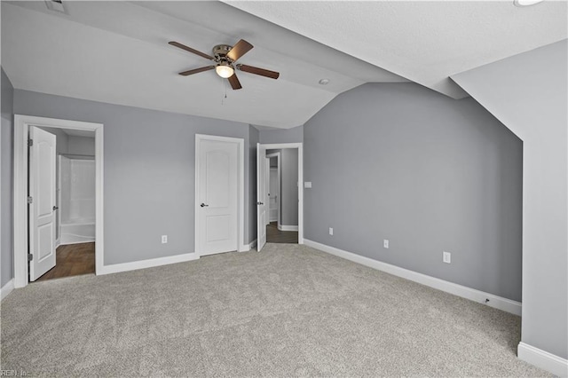 unfurnished bedroom featuring lofted ceiling, carpet, connected bathroom, and baseboards