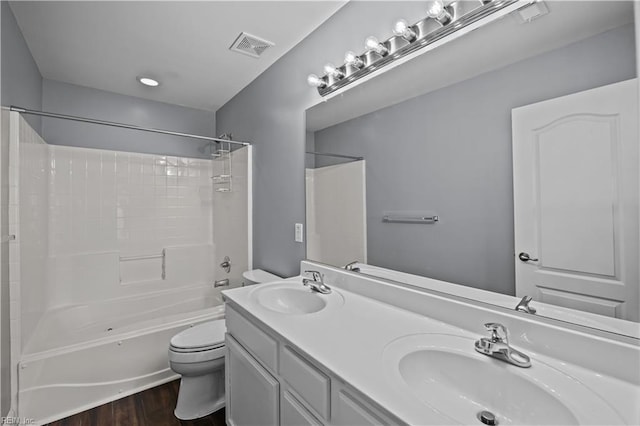 bathroom with toilet, wood finished floors, a sink, and bathing tub / shower combination