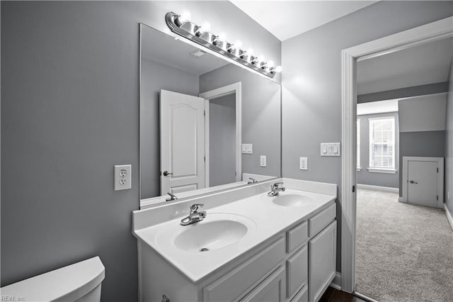 bathroom featuring double vanity, a sink, toilet, and baseboards