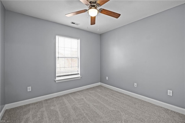 spare room with light colored carpet, visible vents, ceiling fan, and baseboards