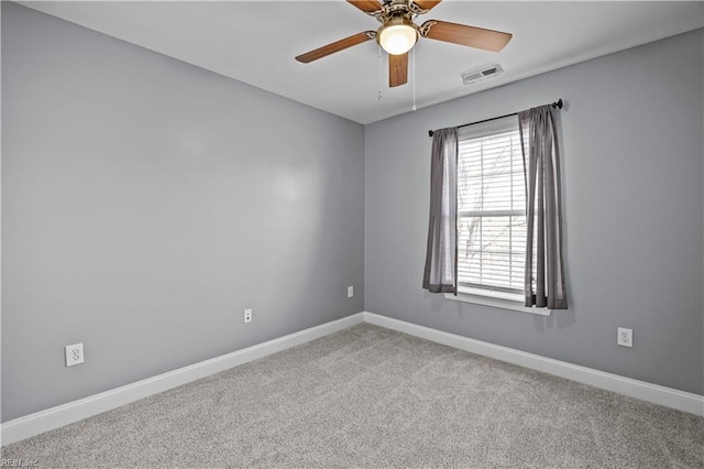 spare room with light colored carpet, ceiling fan, visible vents, and baseboards