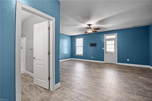 empty room with baseboards, a ceiling fan, and wood finished floors