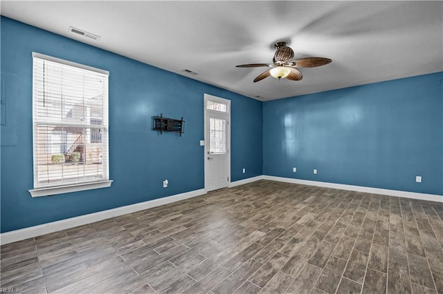 empty room featuring a wealth of natural light, visible vents, and wood finished floors