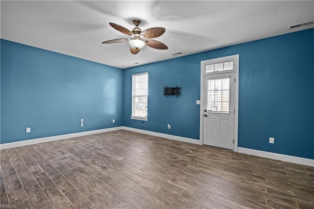 empty room featuring baseboards, visible vents, and dark wood-type flooring