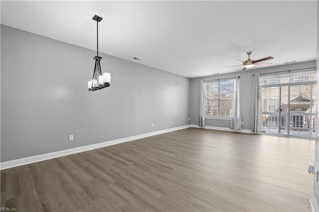 unfurnished room featuring visible vents, baseboards, dark wood-style flooring, and ceiling fan with notable chandelier