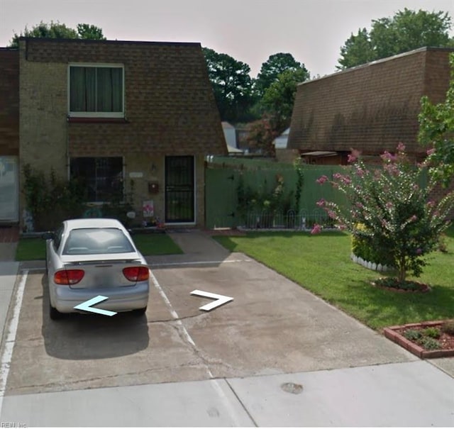 view of front of property featuring uncovered parking, fence, and a front lawn