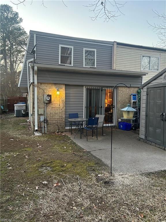 rear view of house featuring a patio, central AC unit, a storage shed, brick siding, and an outdoor structure