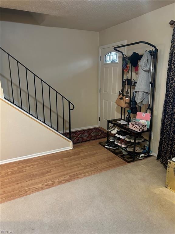 foyer featuring stairway, a textured ceiling, baseboards, and wood finished floors