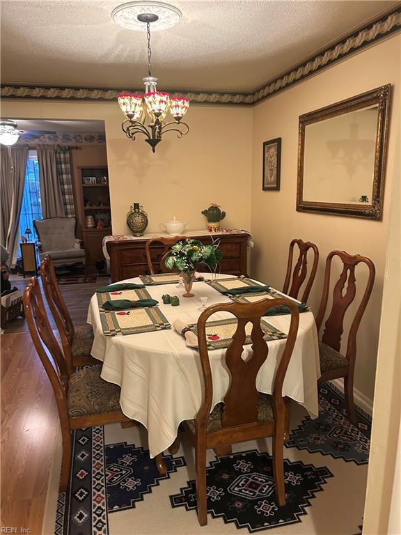 dining room featuring a textured ceiling, wood finished floors, and a chandelier