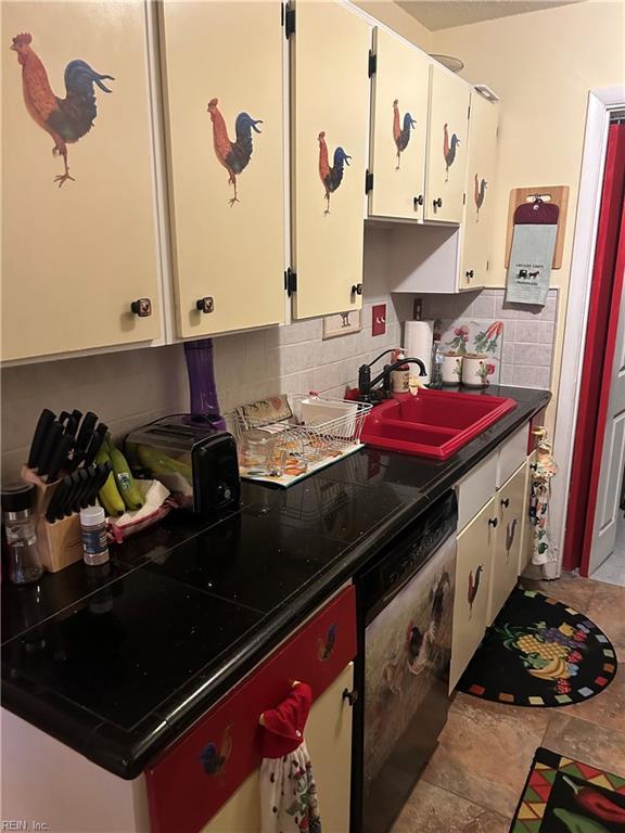 kitchen with white cabinets, decorative backsplash, dark countertops, tile patterned flooring, and a sink