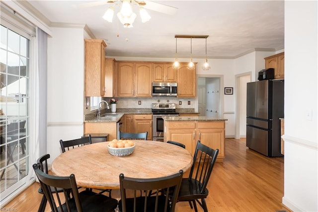 kitchen with a sink, ornamental molding, appliances with stainless steel finishes, light wood-type flooring, and a center island