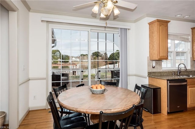 dining room with light wood finished floors, ceiling fan, baseboards, and crown molding