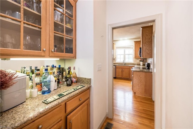 bar with a sink, visible vents, appliances with stainless steel finishes, light wood-type flooring, and a bar