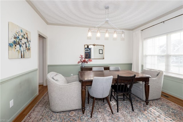 dining space featuring ornamental molding, wood finished floors, and baseboards