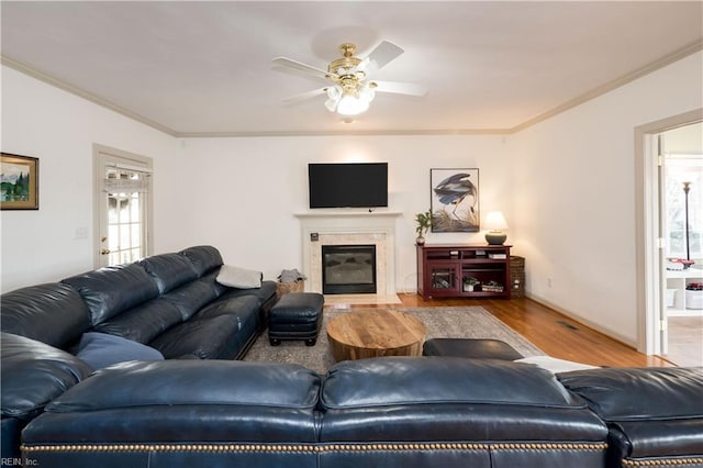 living room with a premium fireplace, wood finished floors, visible vents, a ceiling fan, and ornamental molding