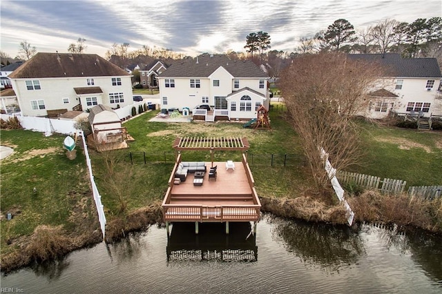 dock area with a lawn, a deck with water view, fence, and a residential view